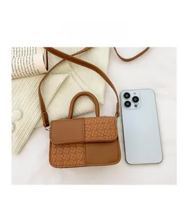Mini sac bandoulière marron posé à côté d'un smartphone pour montrer sa taille compacte