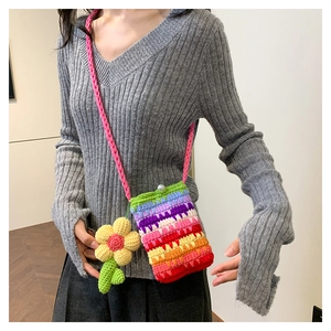 Nahaufnahme der Regenbogen-Häkeltasche mit Blumenanhänger und Perlenknopf-Detail