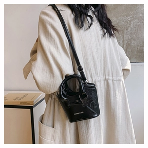 Black oil wax leather mini bucket bag with star charm worn by model in a minimalist setting