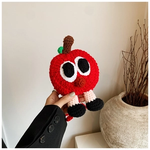 Détail du sac pomme rouge crocheté à la main avec yeux tricotés et décoration feuille