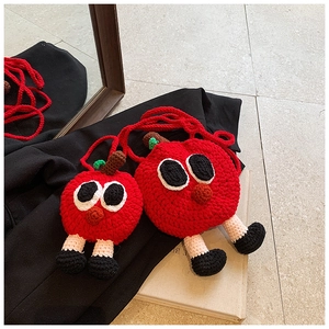 Vue détaillée de sacs pommes rouges crochetés main avec yeux cartoon et pieds tricotés
