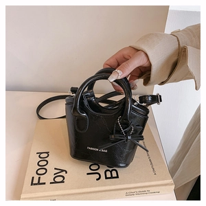 Close-up of black crackle texture mini bucket bag with star charm and fashion text