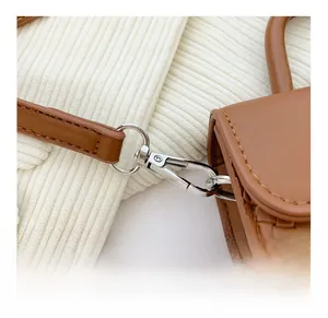 Détail du crochet argenté amovible et texture en cuir tressé du petit sac à main marron