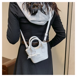 Detailed back view of a white mini leather handbag with bow charm and adjustable strap