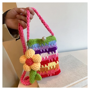 Detail der bunten Häkeltasche mit Blumenanhänger und Perlenverschluss für Damen