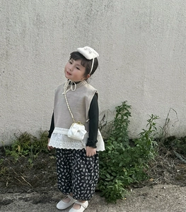 Detail einer weißen gesteppten Umhängetasche mit Schleife auf einem Kinderoutfit