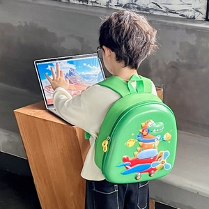 Sac à dos rigide dinosaure vert pour enfant porté par un écolier dans une pièce