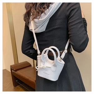 Detailed back view of a white mini bucket bag featuring an elegant bow and star pendant