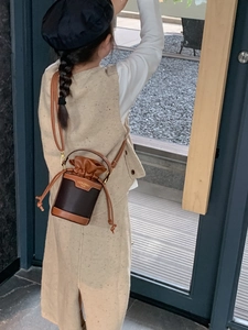 Toddler girl wearing a stylish brown drawstring bucket bag with leather strap