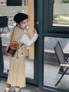 Detail view of a child wearing a stylish brown contrast drawstring bucket bag with chain strap