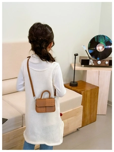 Détail d'un sac bandoulière marron pour enfant avec texture en cuir tressé et lisse