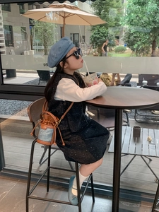 Fashionable girl wearing a navy blue bucket bag and beret set in a cafe setting