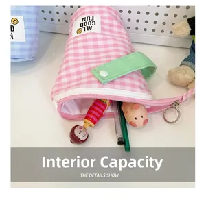 Capacité interne de la trousse rose à carreaux avec stylos et poupée de dessin animé