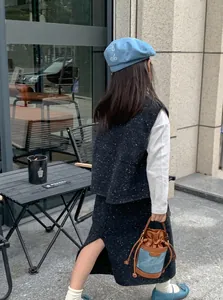 Outdoor shot of a stylish girl's mini drawstring bucket bag with contrast colors and chain