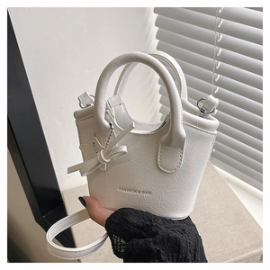 Close-up of white pleated PU handbag with bow charm and Fashion & Bag lettering