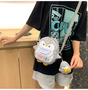 Detail of cute penguin crossbody bag with colorful plush balls in a transparent pocket