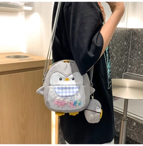 Detail of penguin crossbody bag featuring lace bib, colorful fur balls, and mini plush charm