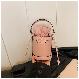 Detail of pink drawstring bucket bag with gold lettering and soft textured faux leather