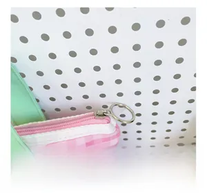 Détail de la fermeture éclair circulaire argentée sur un sac à carreaux rose et blanc