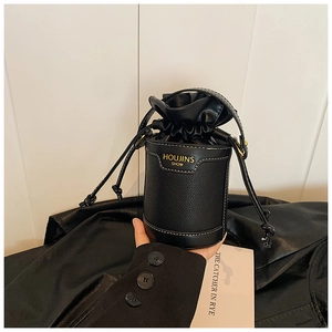 Detail of the litchi grain leather texture and gold logo on the black bucket bag