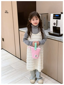 Sac bandoulière à carreaux rose avec poignée verte dans un décor intérieur chic