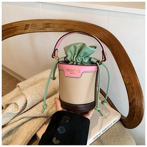 Detail of color-block mini bucket bag with leather texture and elegant drawstring closure