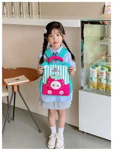 Close-up of strawberry cartoon backpack featuring pink stripes and teal color block design