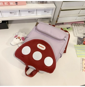 Detail of creative mushroom backpack with red polka dots and DUDU logo on purple fabric