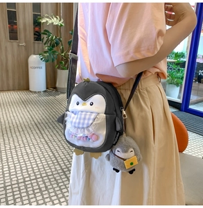 Detail of penguin crossbody bag with transparent PVC window and moving colorful pom poms