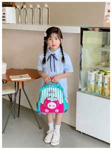 Detail shot of strawberry theme kids backpack held by a girl in a cafe setting