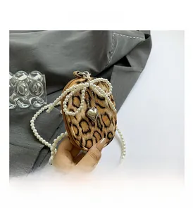 Detail view of leopard print plush mini bag with pearl bow and heart charm accent