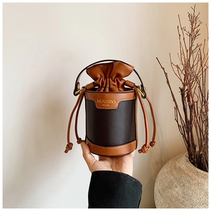 Detail of color-block mini bucket bag with drawstring closure and golden brand text