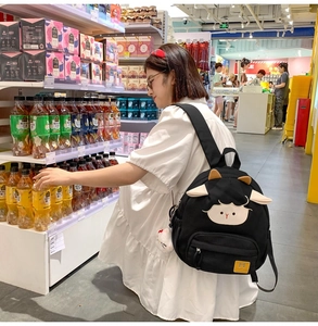 Modellansicht eines schwarzen Canvas-Rucksacks mit Cartoon-Schaf-Design und gelbem Etikett