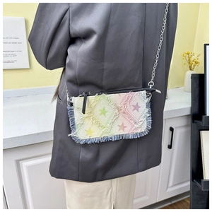 Detail of a denim crossbody bag with star pattern, fringe edges and silver chain strap