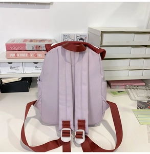 Detail view of purple backpack back with brown straps and white adjustable buckles