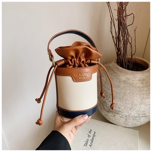 Close-up of a mini contrast color bucket bag with drawstring closure and chain strap