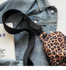 Detail of leopard print chest bag with adjustable nylon strap on denim jacket