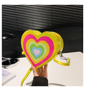 Detail of a yellow heart-shaped crossbody bag with multi-colored heart patterns and silver zipper