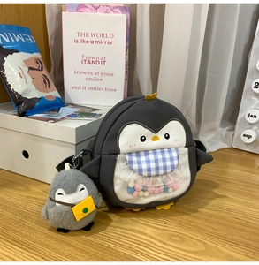 Close-up of cute penguin bag with colorful pom-poms in a transparent front pocket
