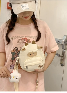 Détail du sac bandoulière mouton crème avec breloque chat en peluche et broderie