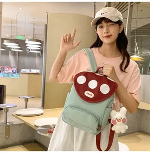 Detail showing mint green mushroom backpack with white polka dots and bunny plush charm