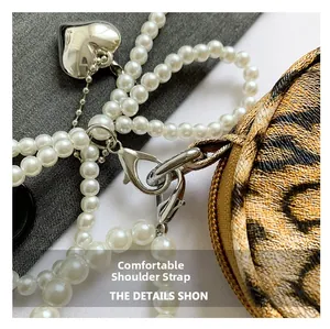 Detail of pearl strap chain with heart pendant and leopard print crossbody bag