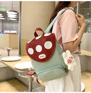 Detail of cute mushroom-themed green backpack with white bunny plush pendant for girls
