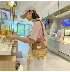 Détail du sac bandoulière poussin mignon avec poche jaune et breloque peluche sur modèle