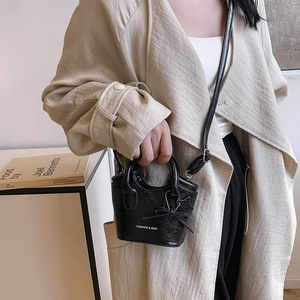 Minimalist black leather mini tote bag with star pendant and chic ribbon detail