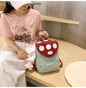 Close-up of a cute mint green mushroom backpack with red polka dot flap and bunny charm