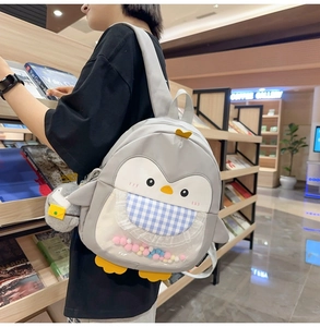 Detailed shot of cartoon penguin backpack with checkered pocket and colorful pom-poms