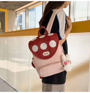 Detail of cute mushroom backpack with red polka dot flap and white bunny keychain