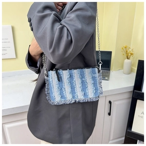Detail view of denim chain shoulder bag with fringe texture and silver metal strap