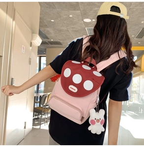 Pink and red mushroom schoolbag with polka dots and rabbit charm on a female model